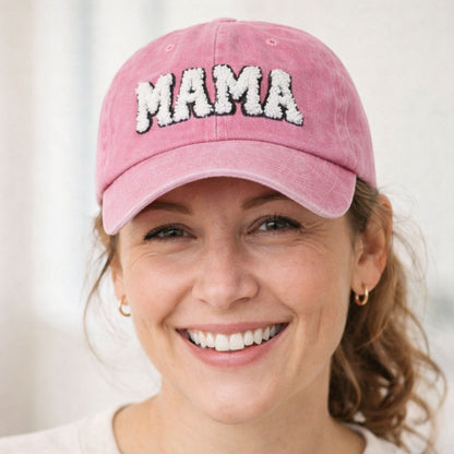 woman wearing pink sherpa letters MAMA baseball hat on a white background.