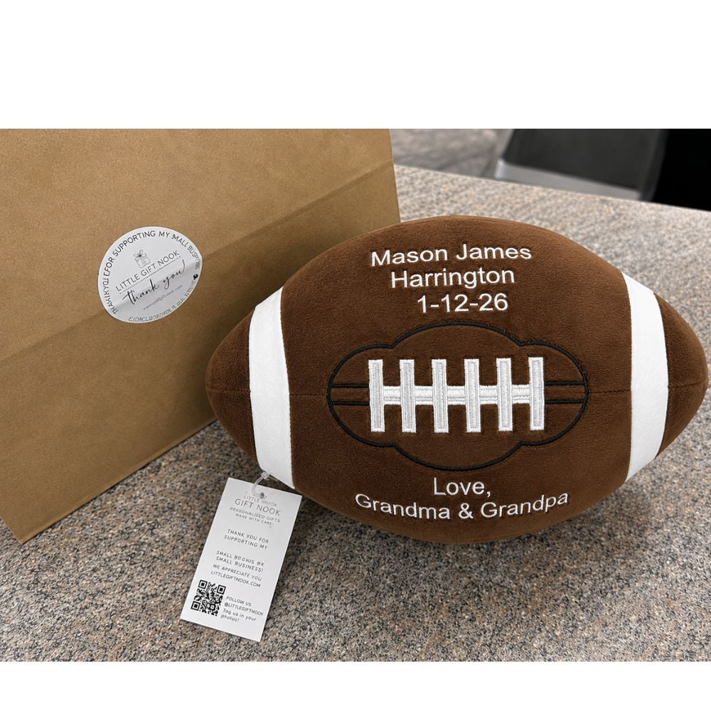 Plush football-shaped pillow with personalized text on a countertop.