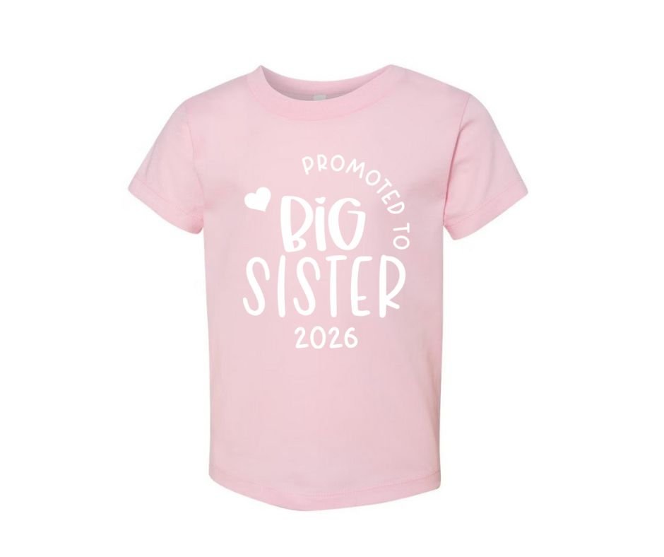 pink kids "promoted to big sister 2026" shirt sitting on white background.