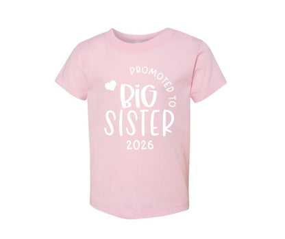 pink kids "promoted to big sister 2026" shirt sitting on white background.