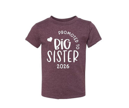 purple "promoted to big sister 2026" tshirt sitting on white background.
