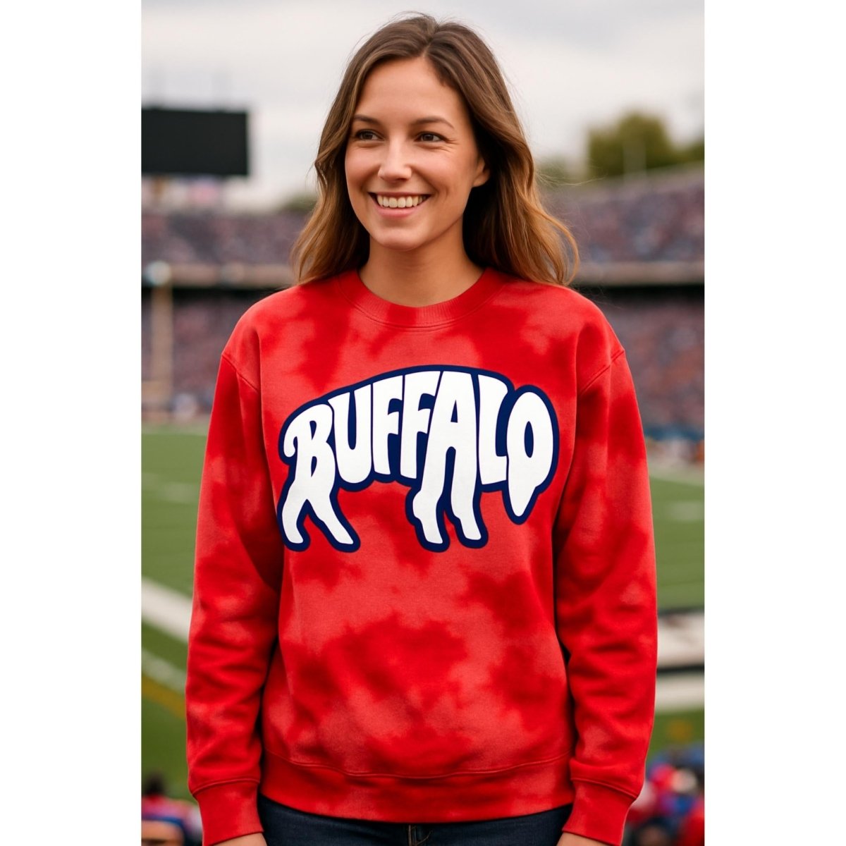 Woman wearing red bleach-dyed crewneck sweatshirt with blue & white buffalo letters in shape of buffalo on front standing on football field background.