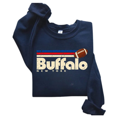 A navy blue sweatshirt with a distressed graphic on the front featuring the text 'Buffalo NEW YORK', horizontal red and white stripes, a football, and the word 'Buffalo' in large cream letters. The sweatshirt is shown folded on a plain white background.