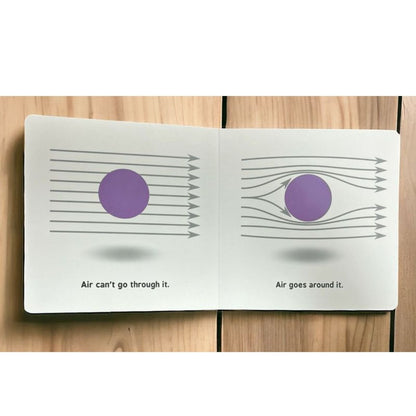 Open book "Rocket Science for Babies" with diagrams and text of balls and air on a wooden surface.
