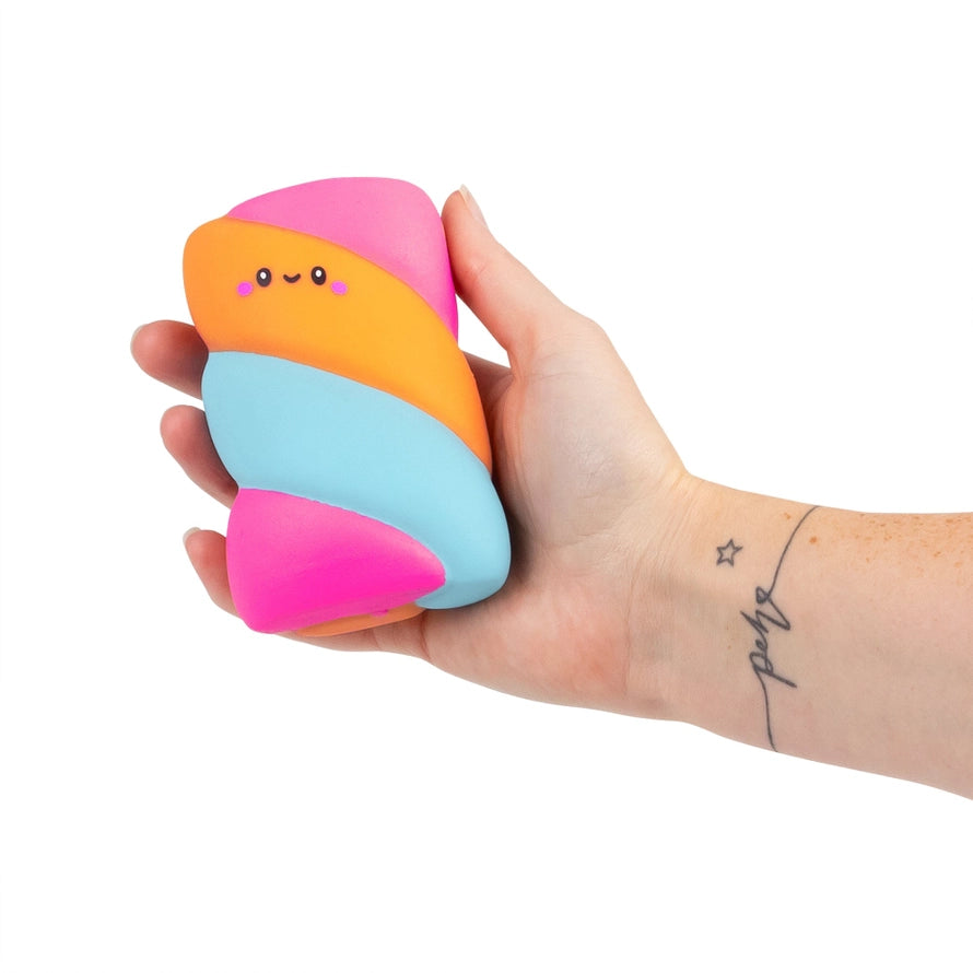 Hand holding Srunchems colorful orange blue and pink striped squishy marshmallow like sensory fidget squeezy toy on a white background.
