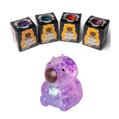 Scrunchems® Sugar Capybara Squishy Fidget Toy in multiple colors in box packaging and purple glitter one sitting on white background.