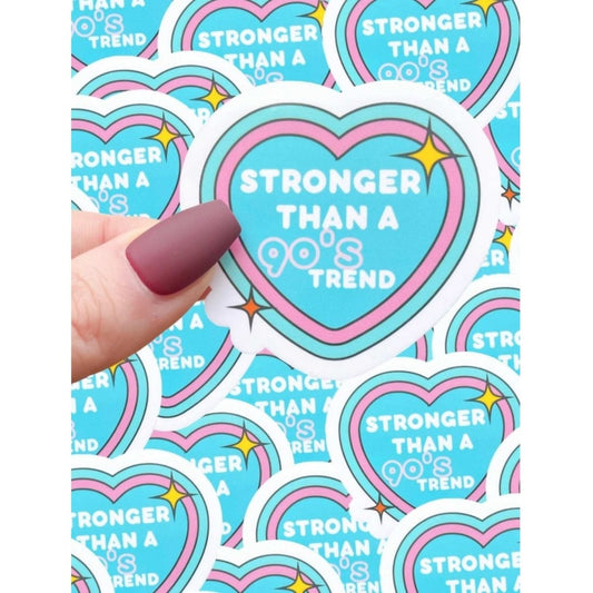 blue pink heart sticker "Stronger than a 90's trend" being held with more of the same stickers in background. Little Gift Nook