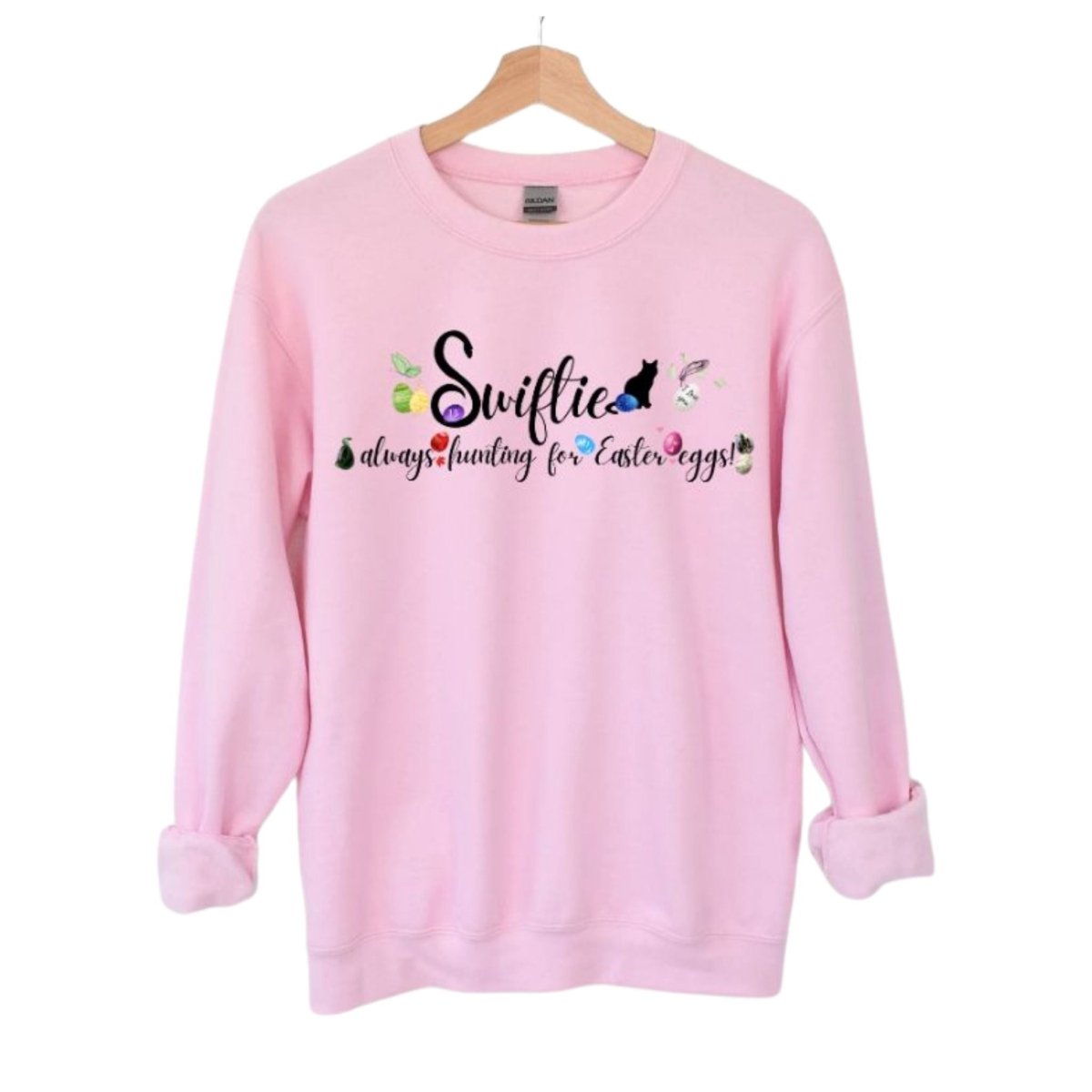 Pink crewneck sweatshirt with Swiftie always hunting for Easter Eggs in black lettering and colored Easter eggs with patterns and items associated with each era.  Little Gift Nook.