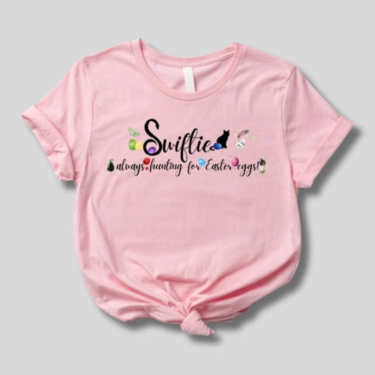 Pink Swiftie always hunting for Easter Eggs Tshirt.  Has black lettering and colored eggs with patterns that are associated with each era.  Little Gift Nook.