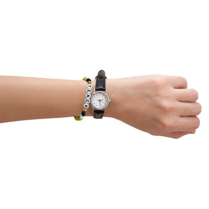 Arm with yellow alphabet beaded Teach bracelet and watch on white background.