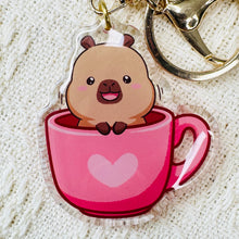 Load image into Gallery viewer, Capybara keychain of cute capybara sitting in pink heart mug. Acrylic, double sided. Little Gift Nook.