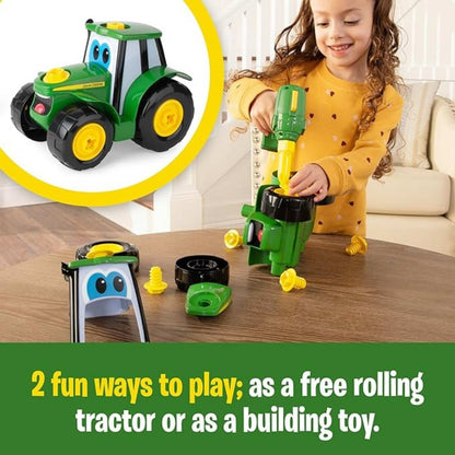 Little girl building a toy plastic John Deere tractor toy with toy drill on brown table top. 