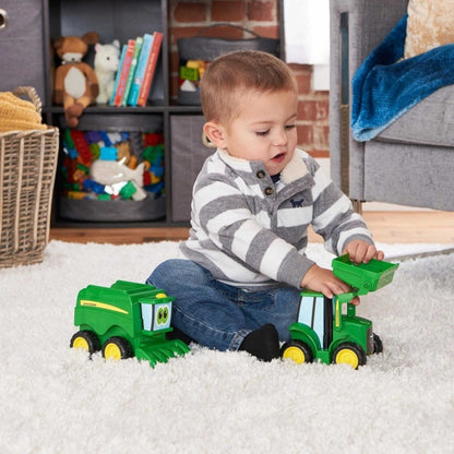 Little boy playing with John Deere 2 piece toy tractor set scoop and haul on white carpet. 