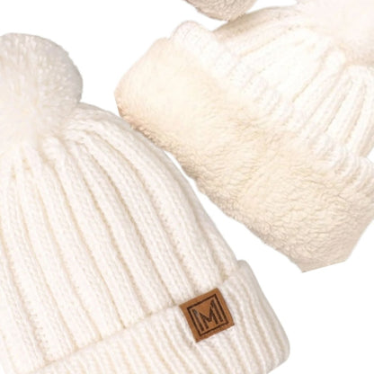 White knit beanie pom hat close up with sherpa lining on a white background.