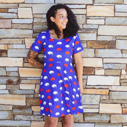 woman in royal blue red and white buffalo print dress standing in front of tan brick wall - Little Gift Nook