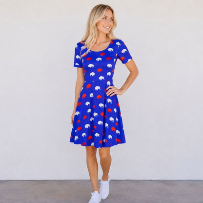 Woman wearing royal blue dress with red and white silhouette buffalo print standing on gray background - Little Gift Nook.