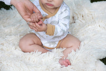 Load image into Gallery viewer, Organic Cotton white, gray, and tan grow with me baby bodysuit. Extra snaps so you get much longer use. Made in India. Close up of bodysuit on model.