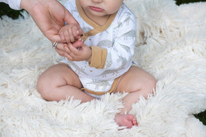 Organic Cotton white, gray, and tan grow with me baby bodysuit. Extra snaps so you get much longer use. Made in India. Close up of bodysuit on model.