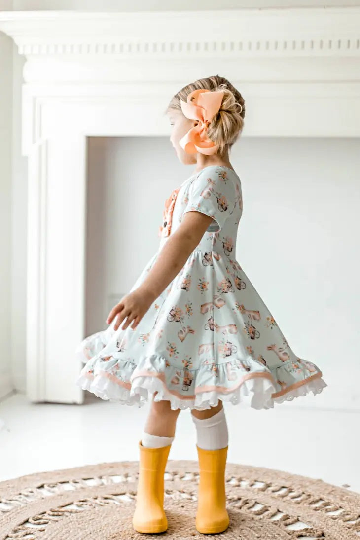 Honey Bunny Blue Eyelet Twirl Dress. Little Girl twirling in light baby blue dress with pink bunnies and flower print. Has eyelet trim.- Little Gift Nook