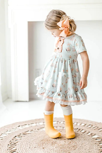 Honey Bunny Blue Eyelet Twirl Dress. Little girl in light baby blue twirl dress with pink bunnies and flower print. Front pockets and eyelet trim.- Little Gift Nook