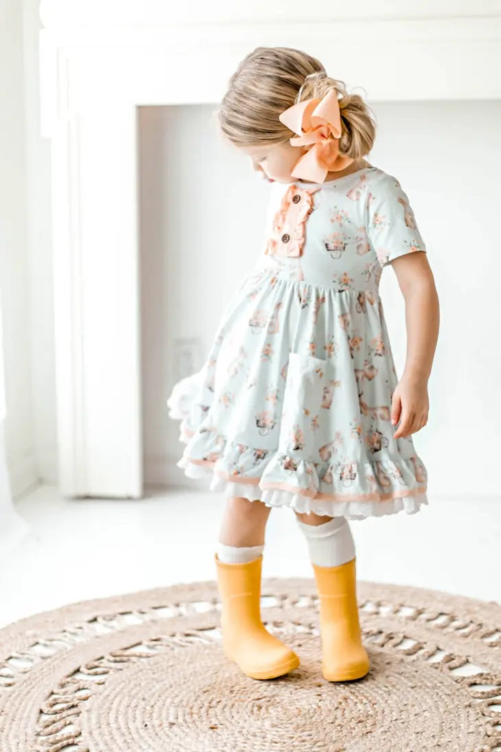 Honey Bunny Blue Eyelet Twirl Dress. Little girl in light baby blue twirl dress with pink bunnies and flower print. Front pockets and eyelet trim.- Little Gift Nook