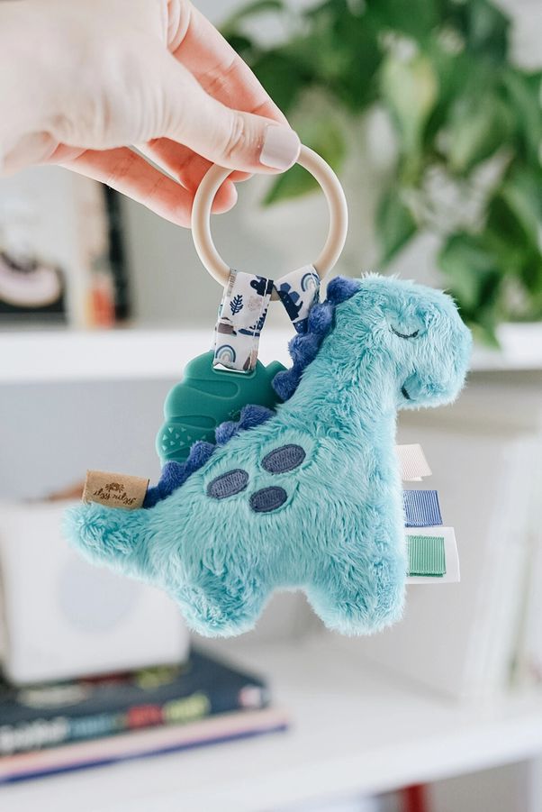 Teal Dinosaur Itzy Pal Plush Teether. Shown held for size comparison. - Little Gift Nook