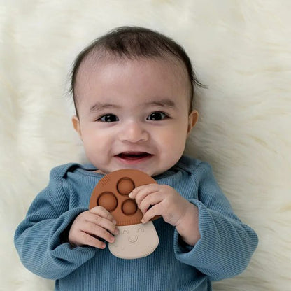 baby holding Itzy Pop Mushroom Teether in brown with sensory bubbles to poke and pop while chewing on silicone teether - Little Gift Nook