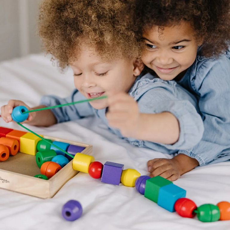 Melissa & Doug Primary Lacing Beads. Toddlers lacing chunky wooden beads onto colored laces. - Little Gift Nook