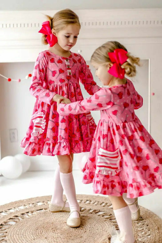 Sucker for Love Hearts Ruffle Twirl Dress. Pink ruffle dress with dark pink heart sucker print and 2 front striped pockets with ruffle edges.  - Little Gift Nook