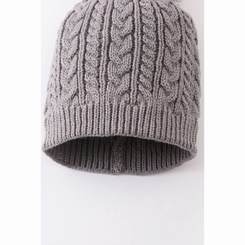 close up of gray cable knit child's hat on white background.