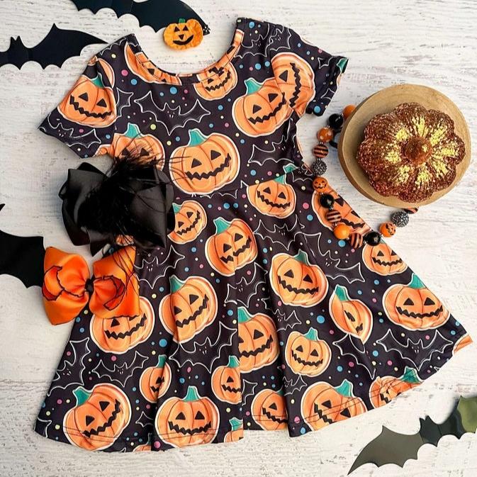 Black orange jack-o-lantern pumpkin bats soft twirl dress on light wood background with hair bows.