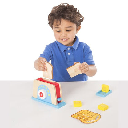 Little boy playing with wooden Melissa & Doug Bread and Butter Toaster Set. 