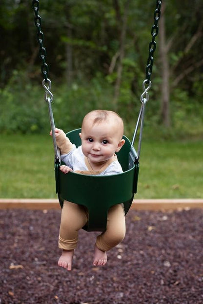 Baby wearing tan cuff legging pants in a baby swing outdoors.