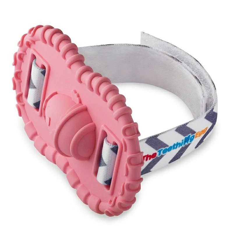 Baby wrist Wristie Teether in Pink with velcro strap sitting on white background. 