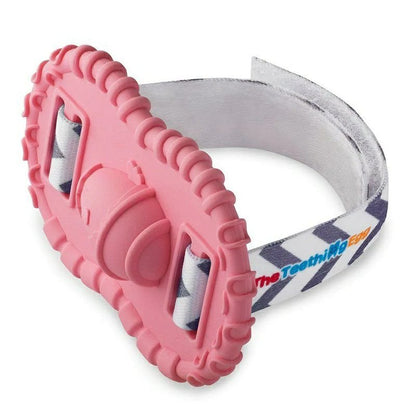 Baby wrist Wristie Teether in Pink with velcro strap sitting on white background. 