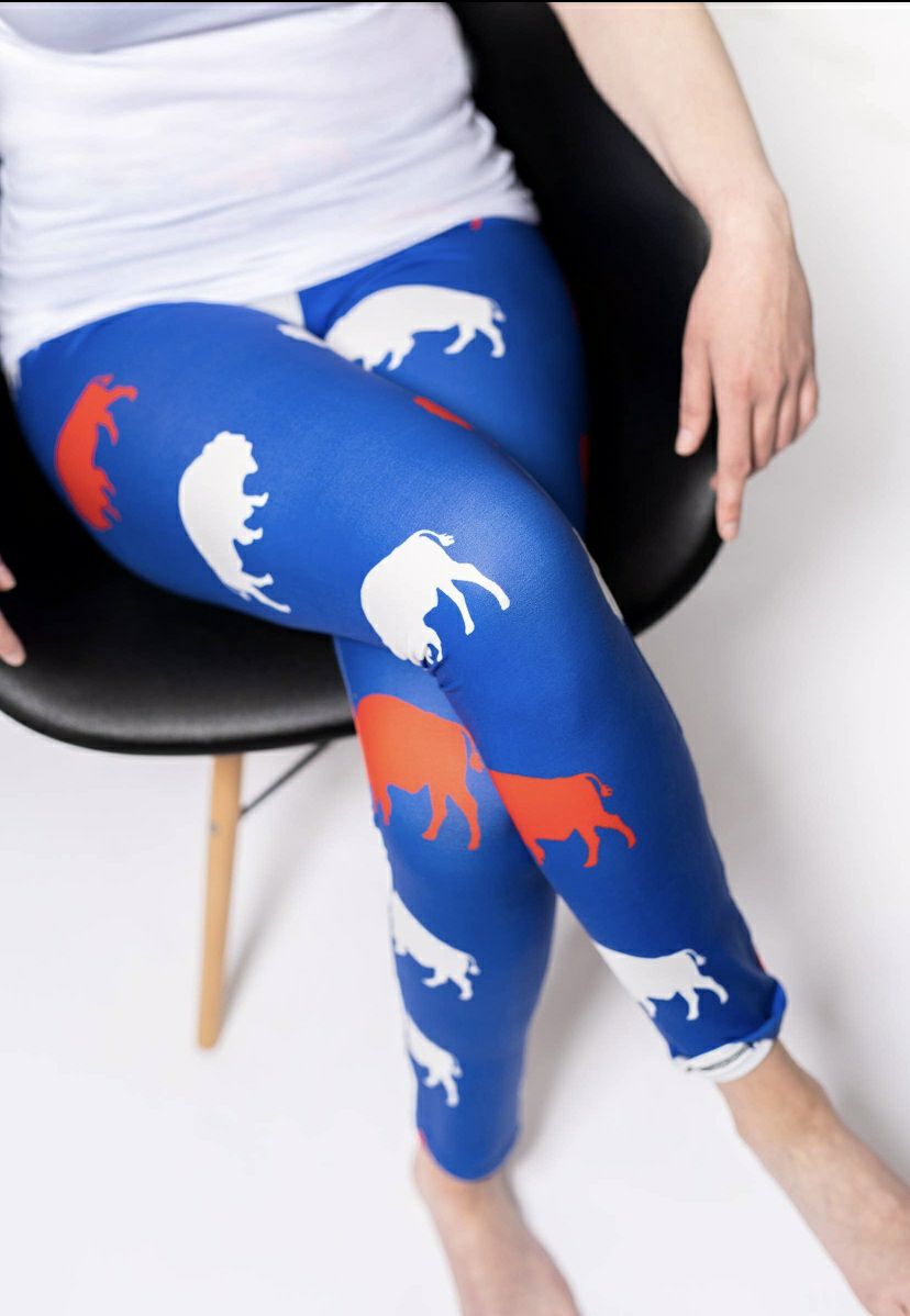 woman in royal blue, red, and white buffalo print leggings sitting cross legged. 