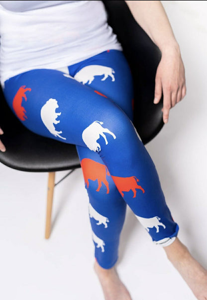 woman in royal blue, red, and white buffalo print leggings sitting cross legged. 